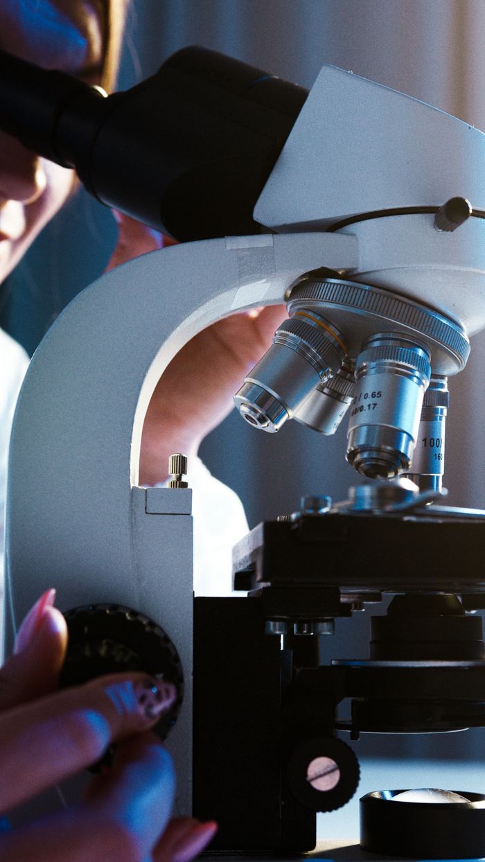 Close-up of a scientist conducting research with a microscope in a laboratory setting.